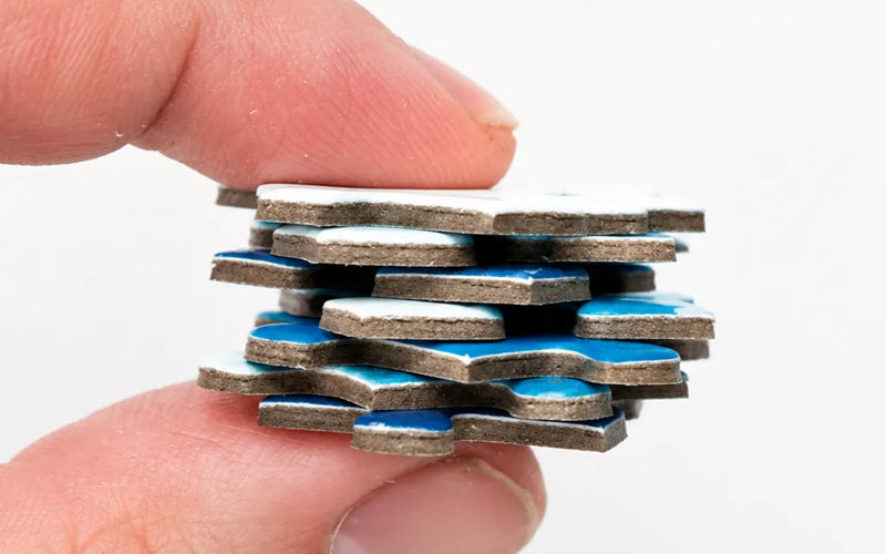 Thick cardboard custom puzzle pieces held between two fingers